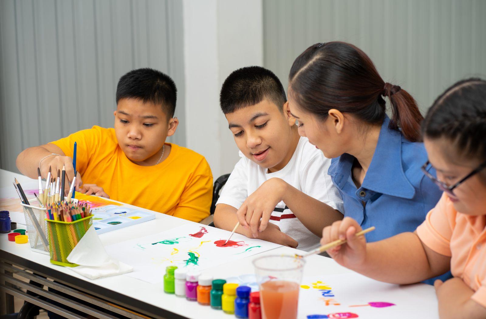 A teacher shows children how to paint