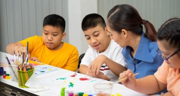 A teacher shows children how to paint