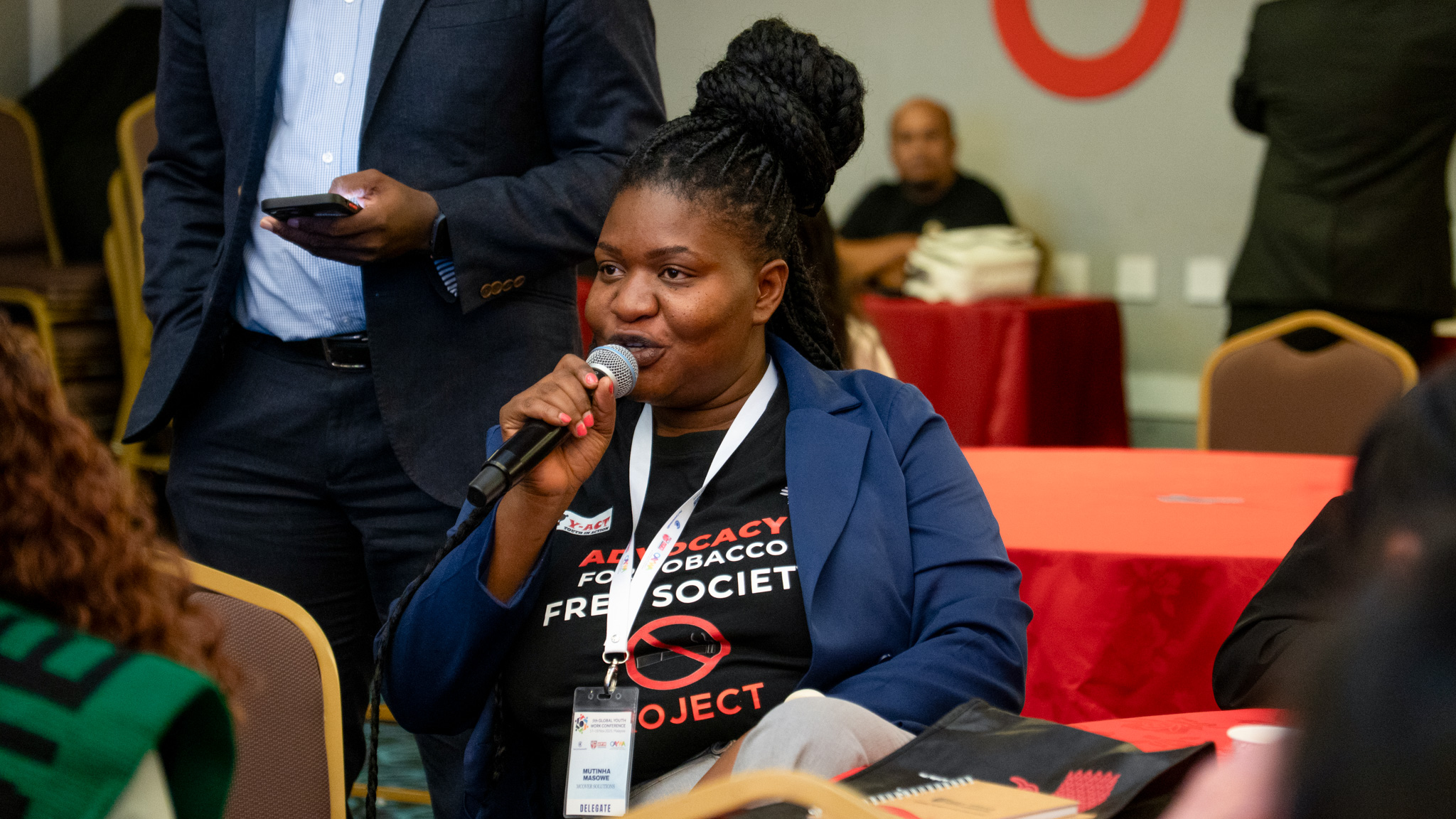 Masowe Mutinta speaking into a microphone at the Global Youth Work Conference