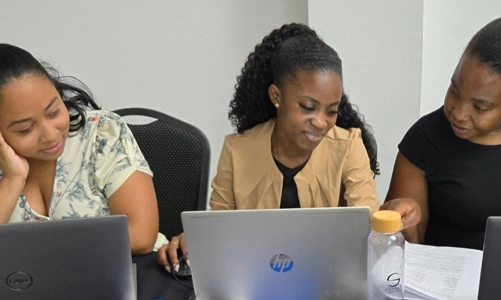 Three female participants work together on a laptop during the workshop