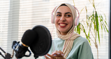 A woman in a hijab speaks into a microphone